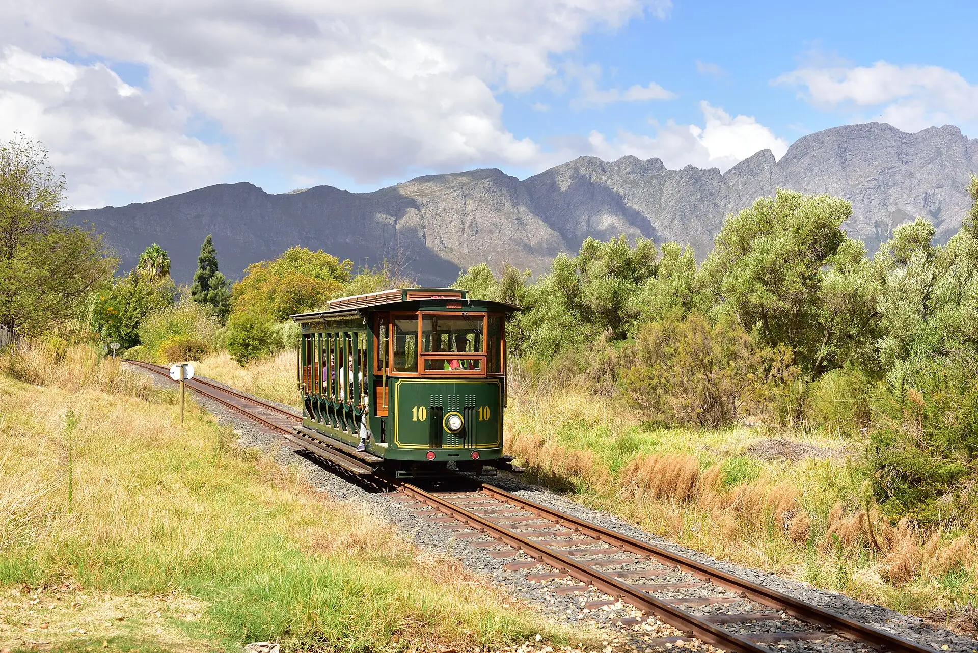 The Franschhoek Wine Tram passing vineyards below the mountains